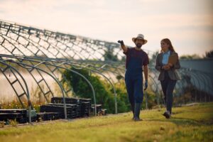 Farm worker and businesswoman talking while walking through his property. Copy space.