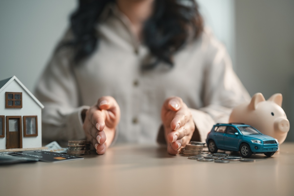 Person managing personal finances by allocating budget across assets like home, car and savings, illustrating expense planning, wealth management and financial control.